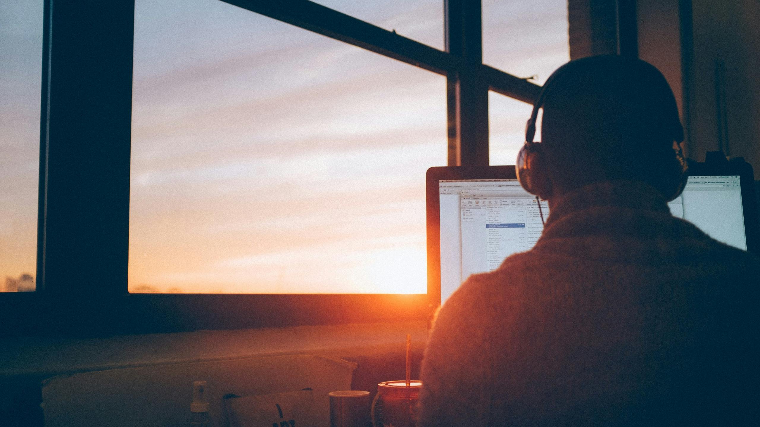 Man working on computer during sunset