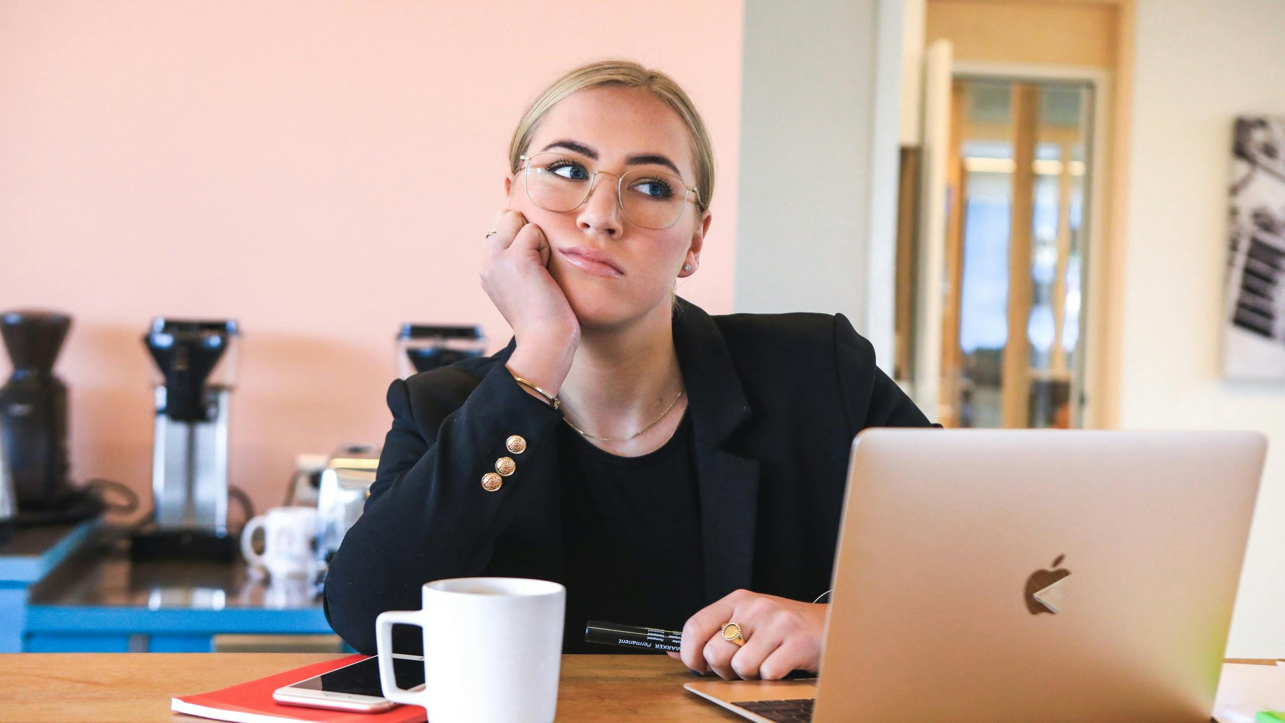 Woman staring into space and procrastinating in front of a laptop