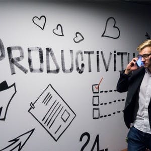 Man on phone walking by productivity sign