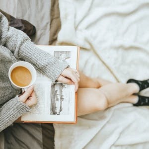 Woman sitting with coffee and book