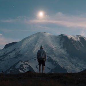 Man staring at sunset over mountaintop