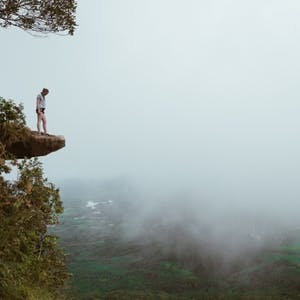 Woman standing on mountain looking into fog