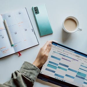 calendars on white table with coffee and glass of water
