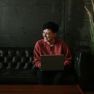 Woman typing on laptop while sitting on couch